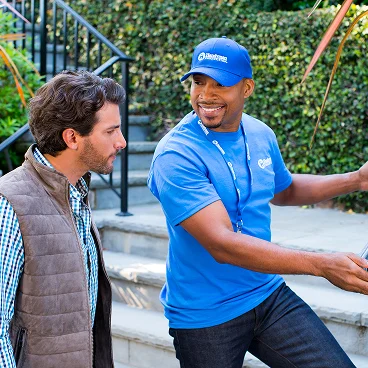 Home service professional discussing deck or porch work with a homeowner outside a house.