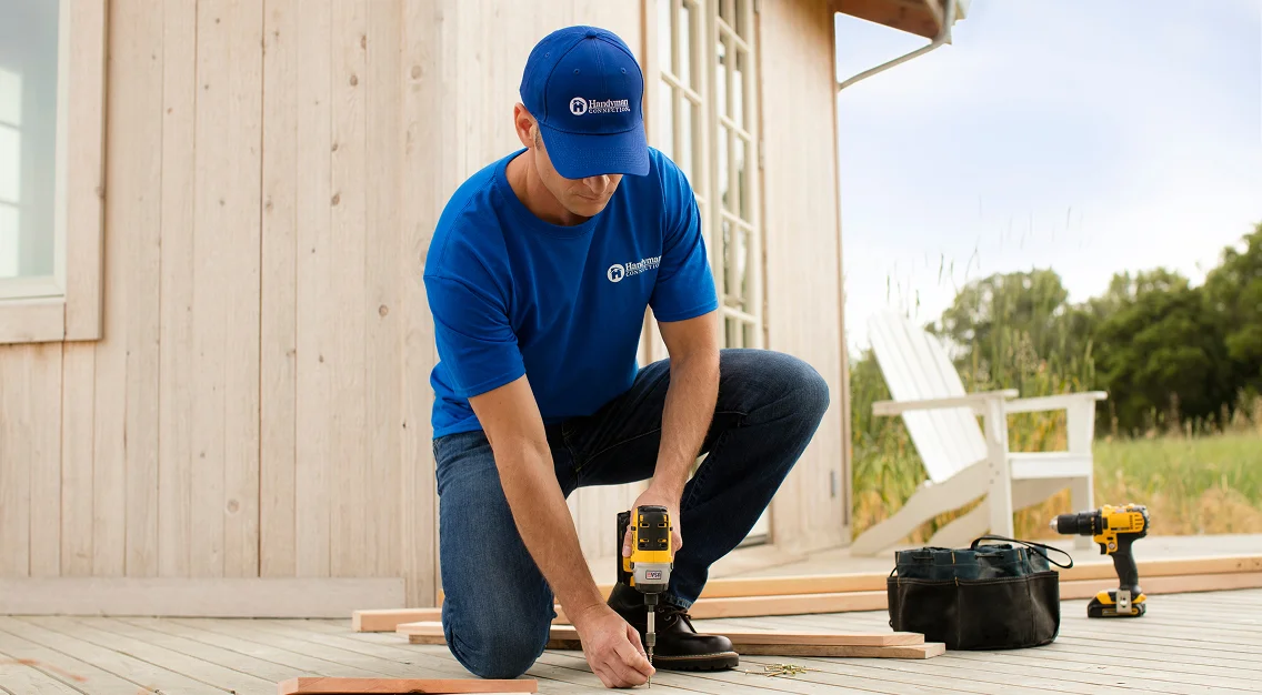 Professional installing deck boards using a power drill during outdoor deck construction.